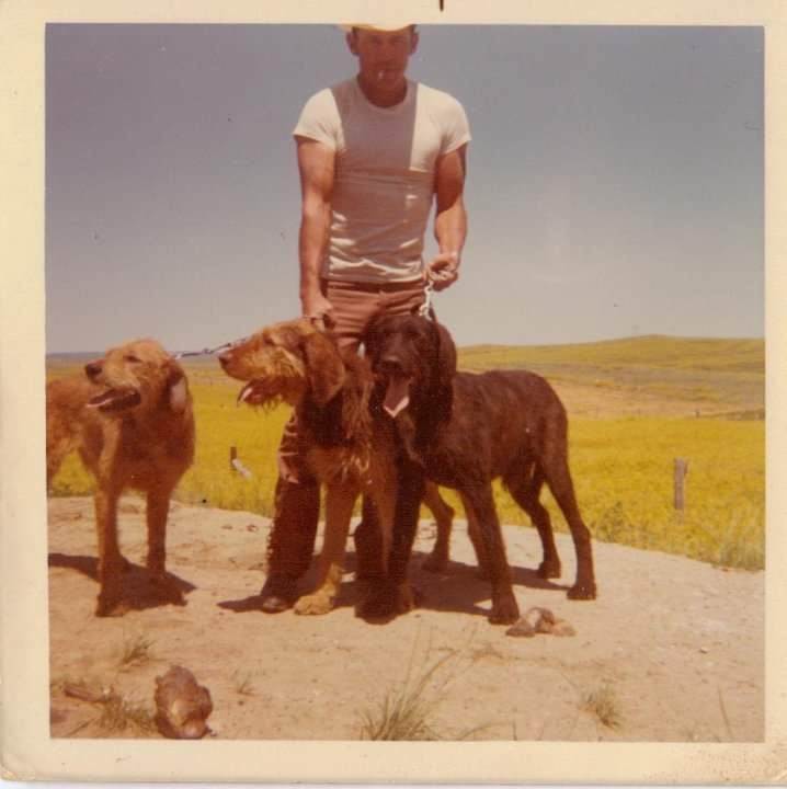 Young Grandpa Nate standing with his three dogs in the desert.