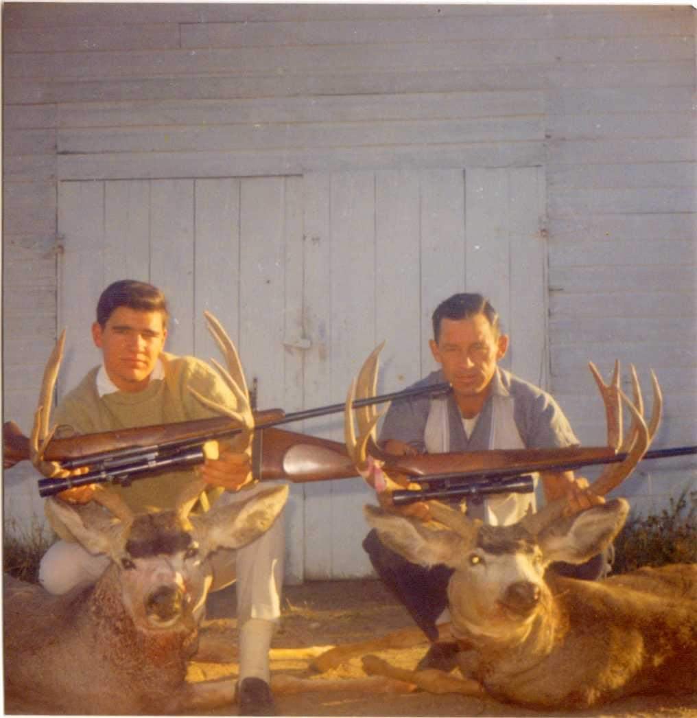 Young Grandpa Nate with another person sitting over two dead animals, holding rifles.
