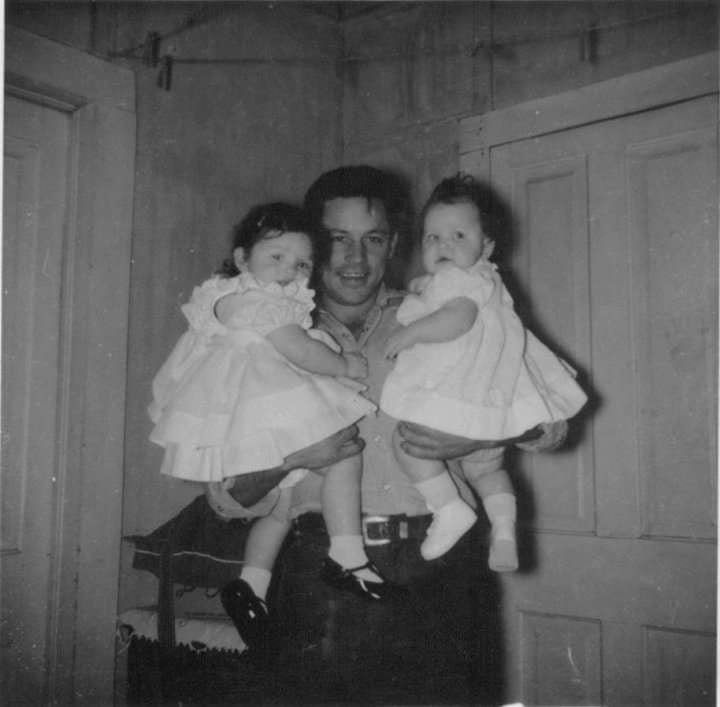 A black and white image of a young Grandpa Nate holding two little girls.